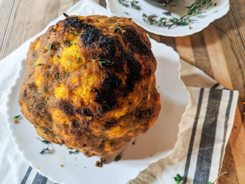 overhead image of a whole roasted cauliflower on a plate