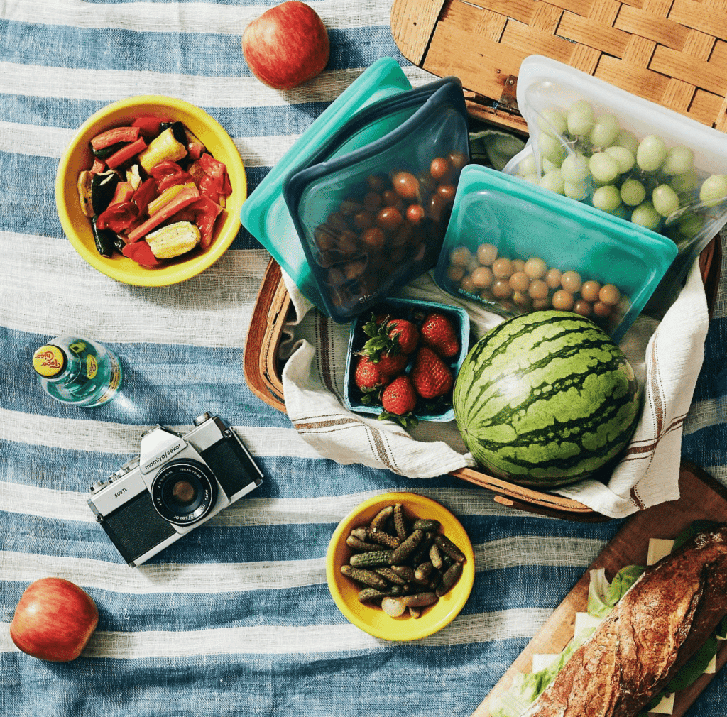 Top view of a picnic spread and camera as part of a beach days essentials list